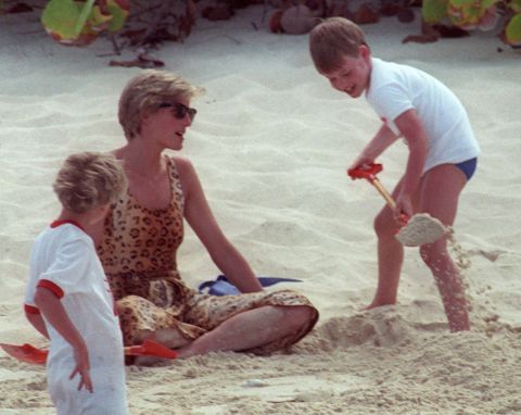 On a private beach in 1990, Prince William shovels sand onto his mother. Photos of the young prince with his adoring mother were common as media interest swelled.