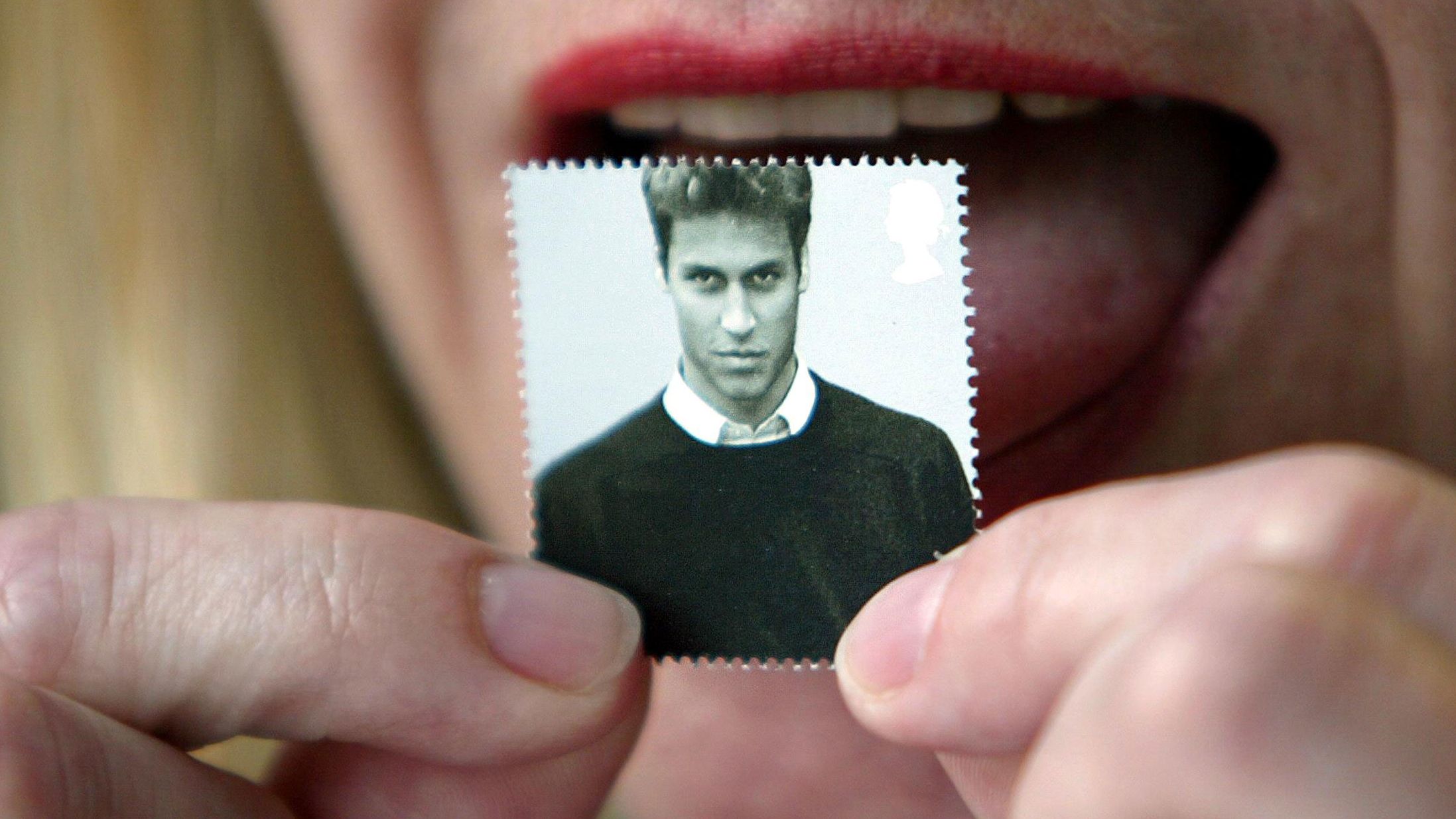 A London office worker licks a first-class stamp that was issued to mark Prince William's 21st birthday in 2003. Commemorative coins were also minted for the occasion.