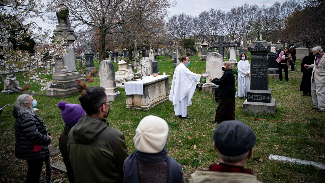 The Rev. John Kellogg, rector of Christ Church, wears a protective mask as he distributes communion at a sunrise Easter service held at the Congressional Cemetery in Washington, DC.