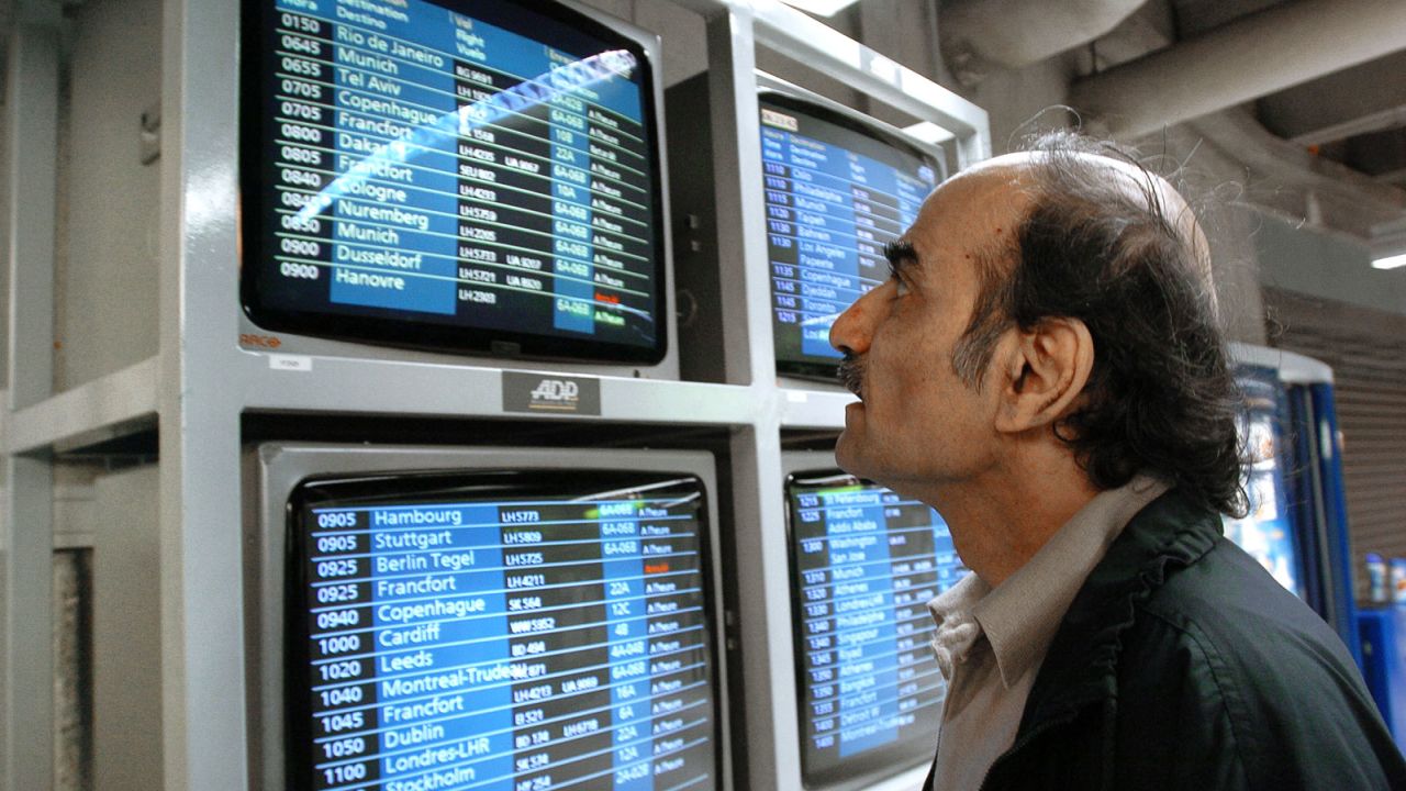 Mehran Karimi Nasseri checks the monitors 12 August 2004 in the terminal one of Paris Charles De Gaulle airport. Known as "Sir Alfred Mehran", Mehran Karimi Nasseri is a 59 year-old Iranian refugee who has been living in Roissy for 16 years, and whose life has therefore inspired American film director Steven Spielberg for the character of the protagonist in the movie "The Terminal". (Photo by STEPHANE DE SAKUTIN / AFP) (Photo by STEPHANE DE SAKUTIN/AFP via Getty Images)