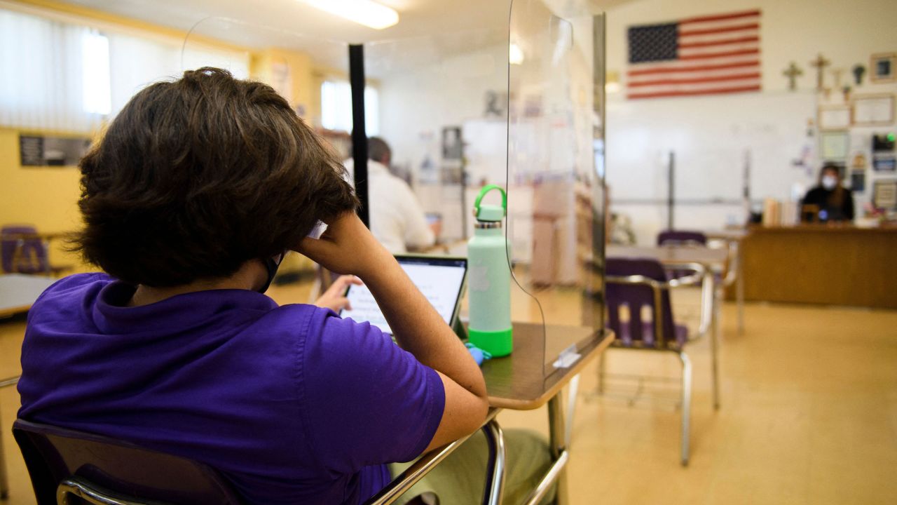 A student sitting behind a barrier works on a tablets as they return to in-person learning at St. Anthony Catholic High School during the Covid-19 pandemic on March 24, 2021 in Long Beach, California. - The school of 445 students implemented a hybrid learning model, with approximately 60 percent of students returning to in an in-person classroom learning environment with Covid-19 safety measures including face masks, social distancing, plexiglass barriers around desks, outdoor spaces, and schedule changes. (Photo by Patrick T. FALLON / AFP) (Photo by PATRICK T. FALLON/AFP via Getty Images)