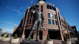A scuplture entitled "The Player" by George Lundeen stands outside the main entracne to Coors Field, home of Major League Baseball's Colorado Rockies, as the sidewalks stand empty on the league's scheduled opening day for the 2020 season with a statewide stay-at-home order taking effect to reduce the spread of the new coronavirus Thursday, March 26, 2020, in Denver. The new coronavirus causes mild or moderate symptoms for most people, but for some, especially older adults and people with existing health problems, it can cause more severe illness or death. (AP Photo/David Zalubowski)