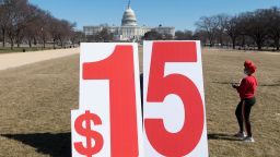 A woman walks past a large sign during an event commemorating International Women's Day and calling for a $15 minimum wage increase on the National Mall in Washington, DC on March 8, 2021. 