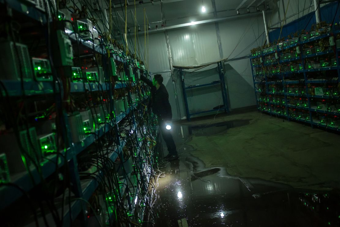 A bitcoin miner inspects a malfunctioning mining machine during his night shift at a bitcoin mine in Sichuan Province, China, on September 26, 2016. 