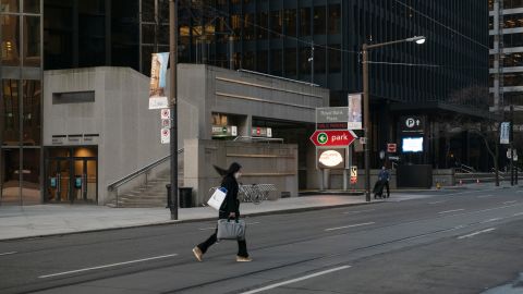 A pedestrian walks across Wellington Street West in Toronto on Thursday, March 25, 2021. 