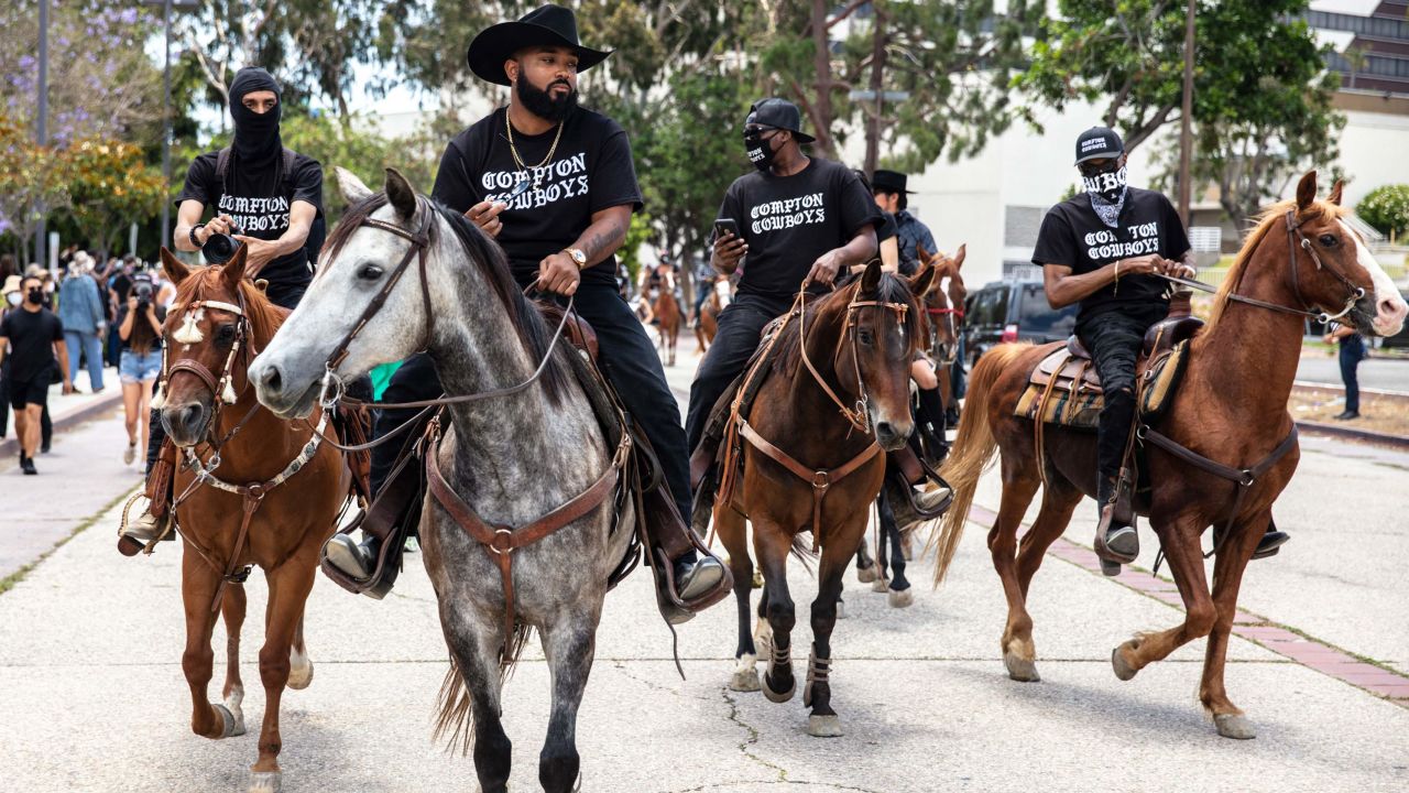 The Compton Cowboys, with Randy Hook at the front, riding in their city near Los Angeles. 