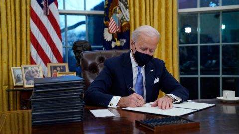 President Joe Biden signs his first executive orders in the Oval Office on Wednesday, January 20, 2021, in Washington. 