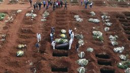 Cemetery workers wearing protective gear lower the coffin of a person who died from complications related to COVID-19 into a gravesite at the Vila Formosa cemetery in Sao Paulo, Brazil, Wednesday, April 7, 2021. 