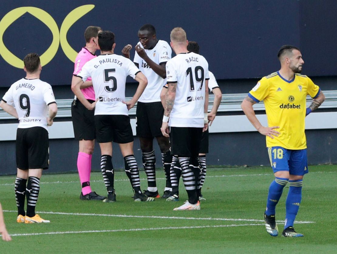 Valencia's defender Diakhaby (middle) talks with the referee after allegedly receiving a racist comment by Cadiz's defender Juan Cala (unseen).