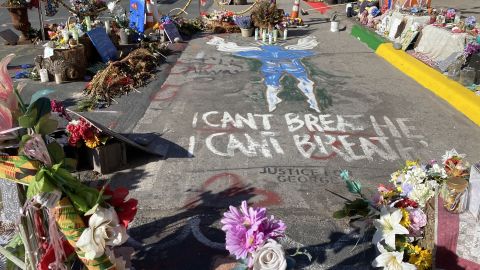 Flowers and candles ring an image of an angel, face down with hands behind back, where Floyd was pinned down by police.