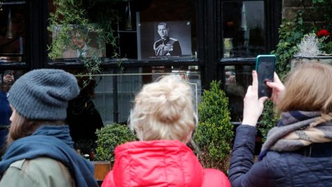People take cellphone photos of a portrait of Prince Philip in a pub window near Windsor Castle on Saturday.