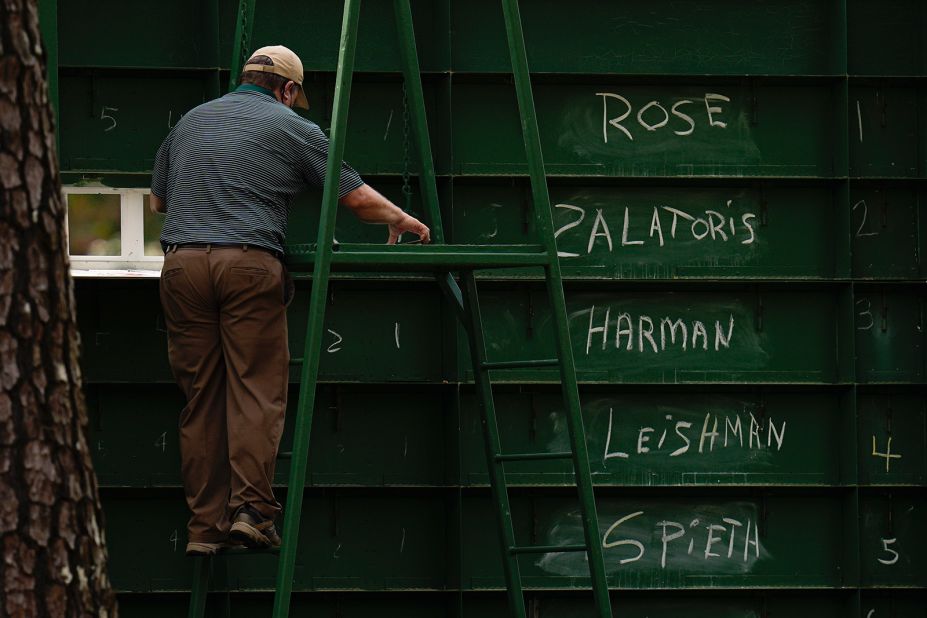 An attendant adjusts scores from behind a leaderboard on Saturday.