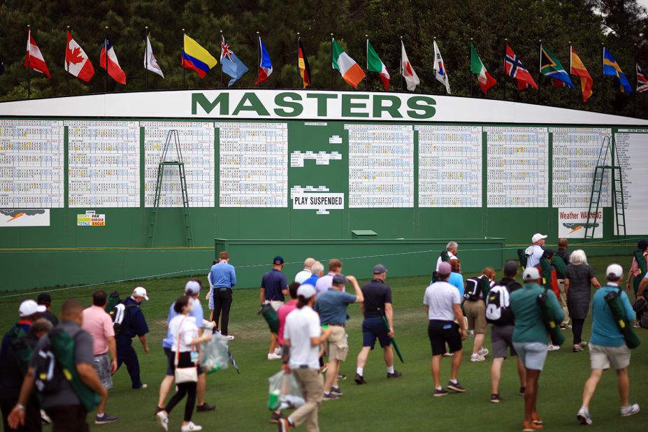 Spectators walk to cover on Saturday after play was temporarily suspended because of inclement weather.