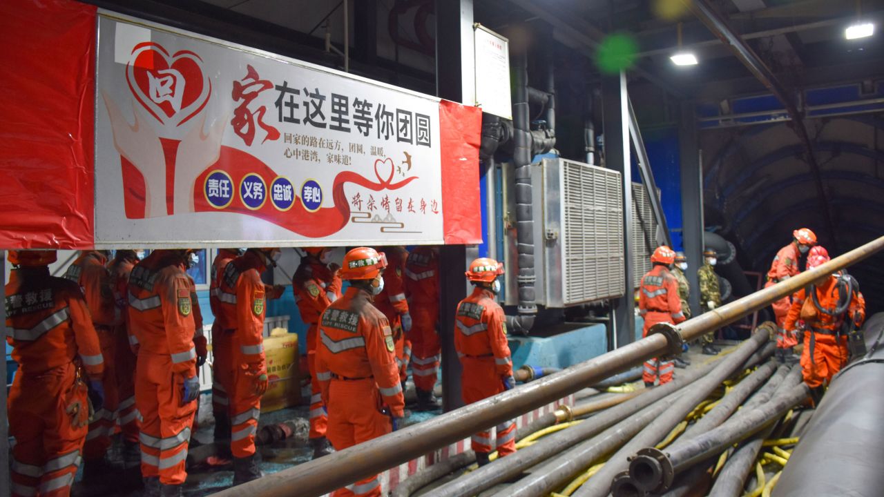 Rescue workers stand near a banner which reads "home is waiting for your return" at the entrance to a flooded coal mine in Hutubi county in Xinjiang on Sunday.