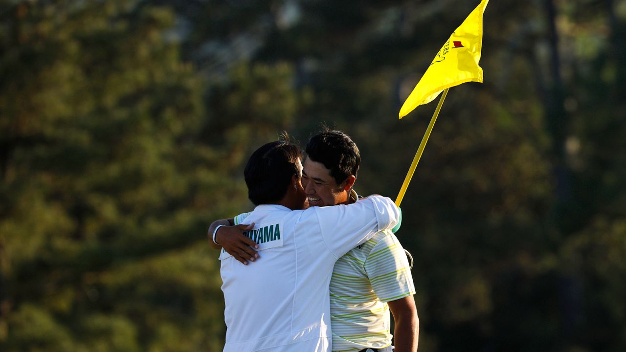 Matsuyama celebrates with his caddie on the 18th green after winning The Masters.