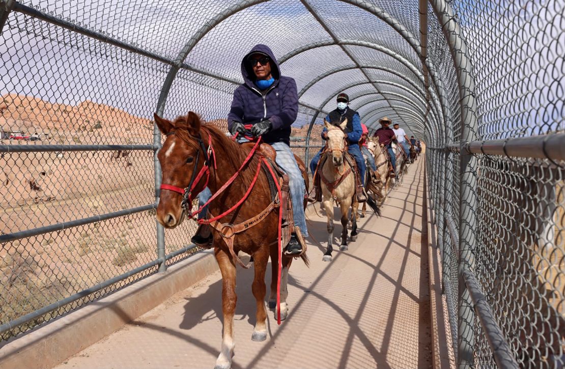 Voters on horseback, riding with Protect the Sacred's Ride to the Polls Election Day initiative, trot over a bridge entering Kayenta, Arizona, on Election Day to cast their votes.