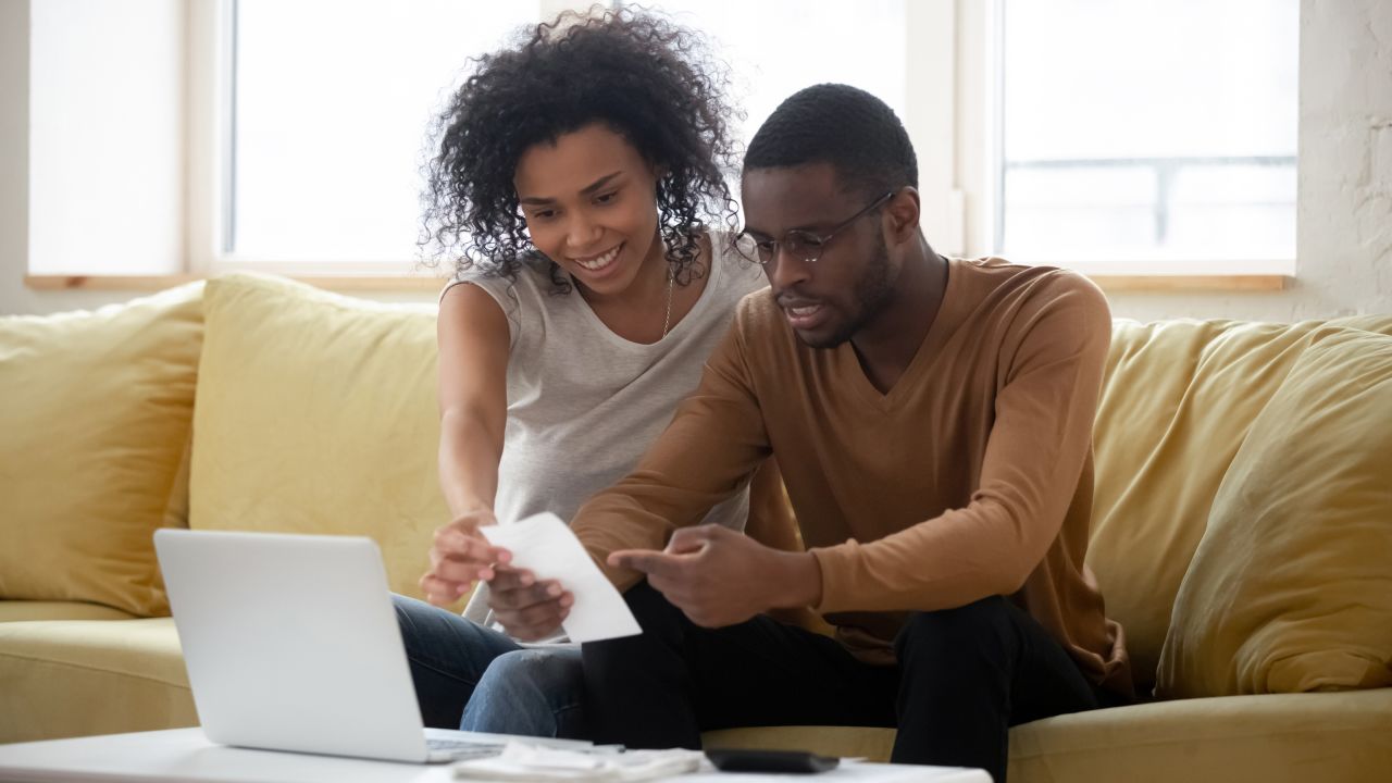 underscored black couple looking at lower mortgage payment with laptop