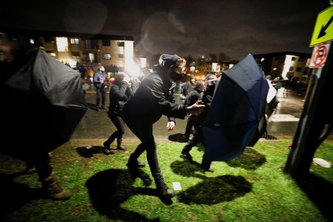 Some protesters advance toward officers Monday using umbrellas as shields.