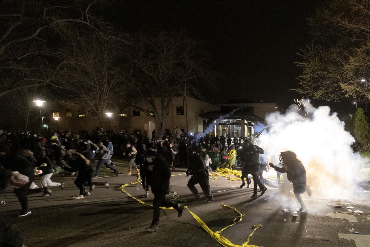 People run as police try to disperse a crowd at the Brooklyn Center Police Department on Sunday.