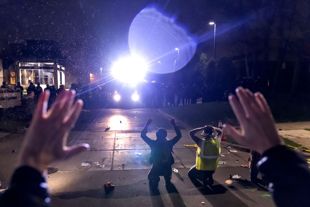 Protesters shout "don't shoot" while kneeling and raising their arms in front of police on Sunday.