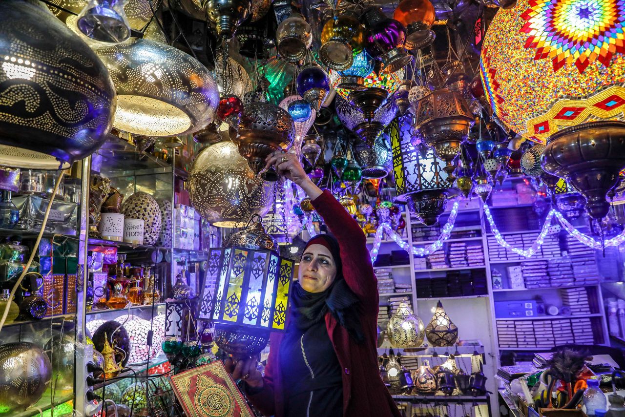 A Palestinian shopkeeper hangs a Ramadan lantern at her shop in the Old City of Jerusalem.