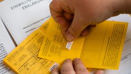 A healthcare worker records a vaccination with the AstraZeneca Covid-19 vaccine on an additional Covid-19 vaccinations card to the International Certificate of Vaccination or Prophylaxis (ICVP), also known as the Carte Jaune or Yellow Card, by the World Health Organization (WHO), at the university hospital in Halle/Saale, eastern Germany, on February 12, 2021. (Photo by JENS SCHLUETER / AFP) (Photo by JENS SCHLUETER/AFP via Getty Images)