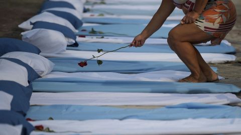 A woman lays a rose on top of a mattress symbolizing Covid-19 victims during a protest outside a hospital in Rio de Janeiro, Brazil, on March 24, 2021.