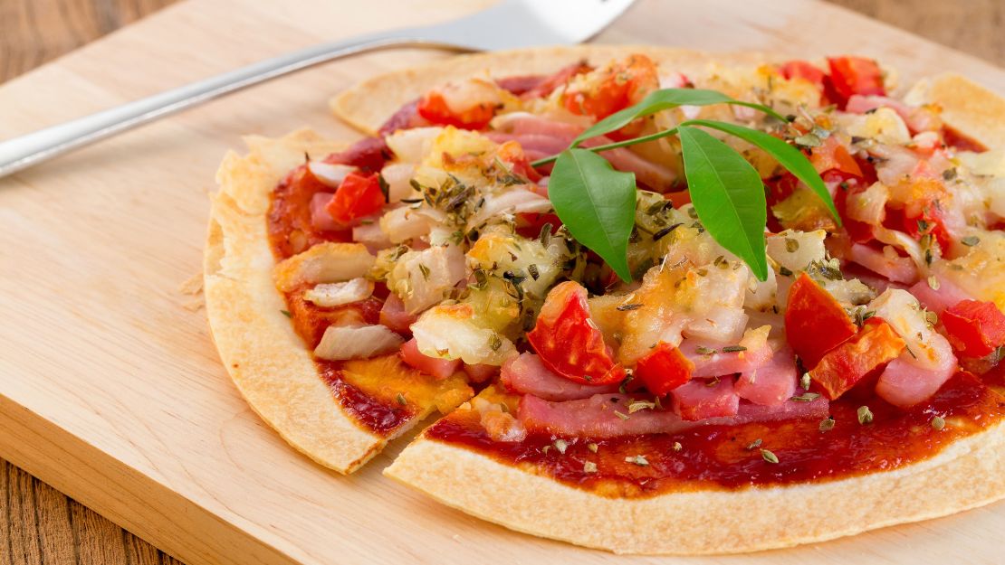 Make a personal pan pizza with a tortilla topped mozzarella, pepper, and basil.