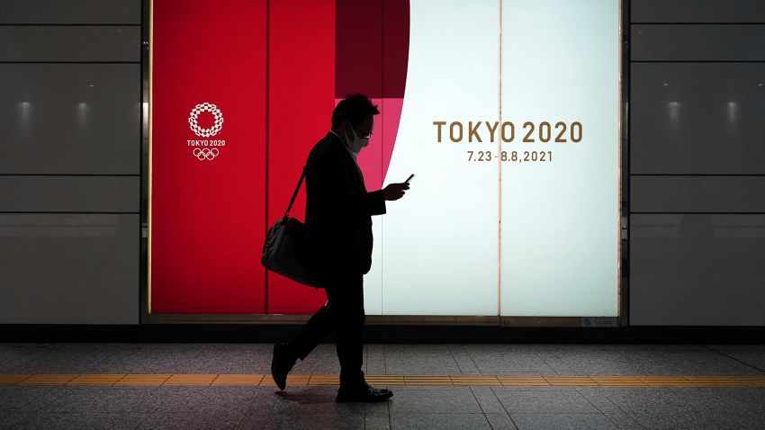 A man wearing a protective mask to help curb the spread of the coronavirus walks near advertisement for Tokyo 2020 Olympics at an underpass Tuesday, April 6, 2021, in Tokyo. The Japanese capital confirmed more than 390 new coronavirus cases on Tuesday. (AP Photo/Eugene Hoshiko)