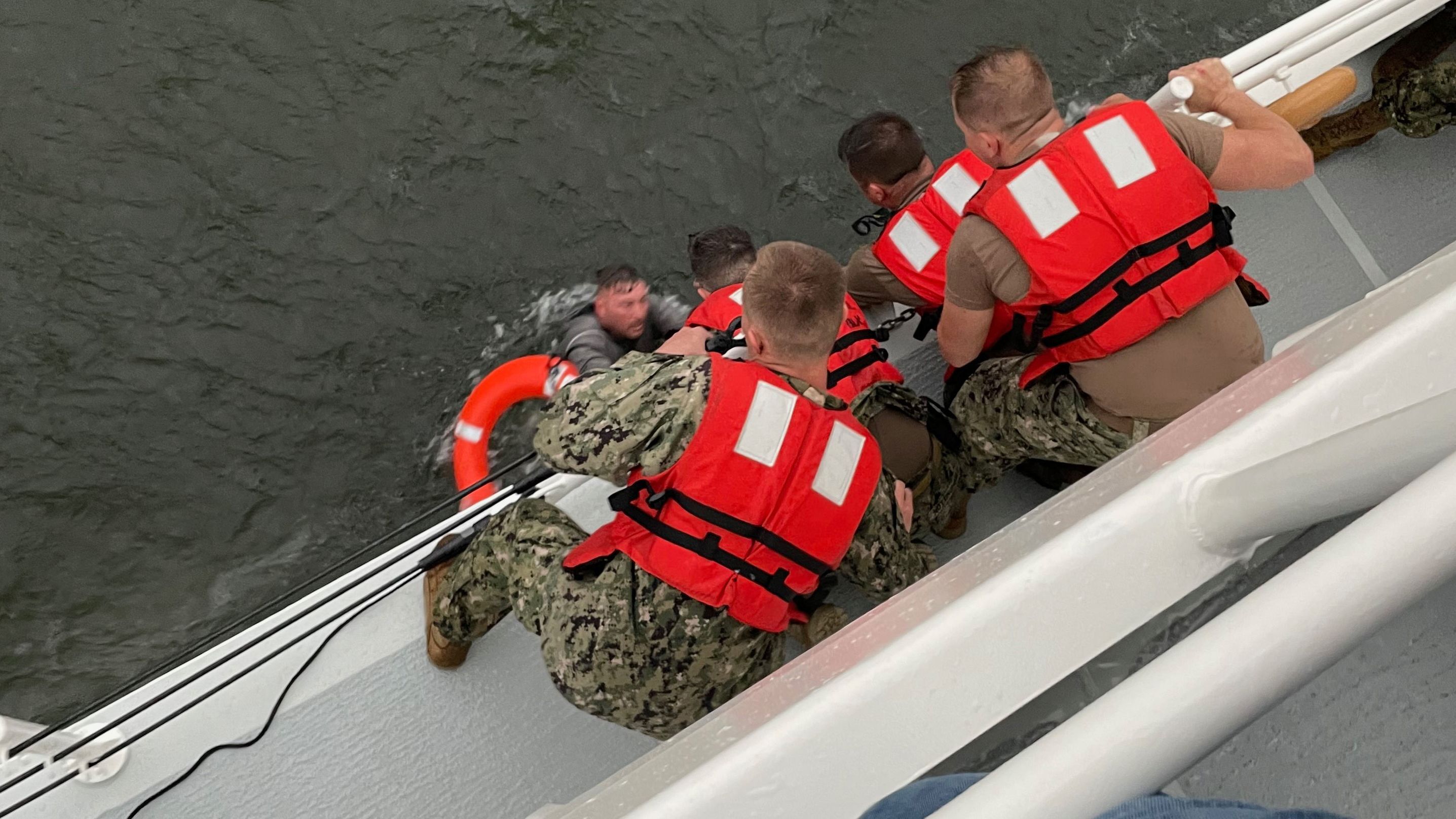 Crew members of the Coast Guard cutter Glenn Harris pull a person from the water after a 129-foot commercial liftboat capsized off the Louisiana coast on Tuesday, April 13.