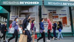 People wearing face masks walk past the Bed Bath & Beyond store. Bed Bath & Beyond has announced plans to permanently close about 200 stores over the next two years. This announcement appears to be the first iteration of that plan, report says.