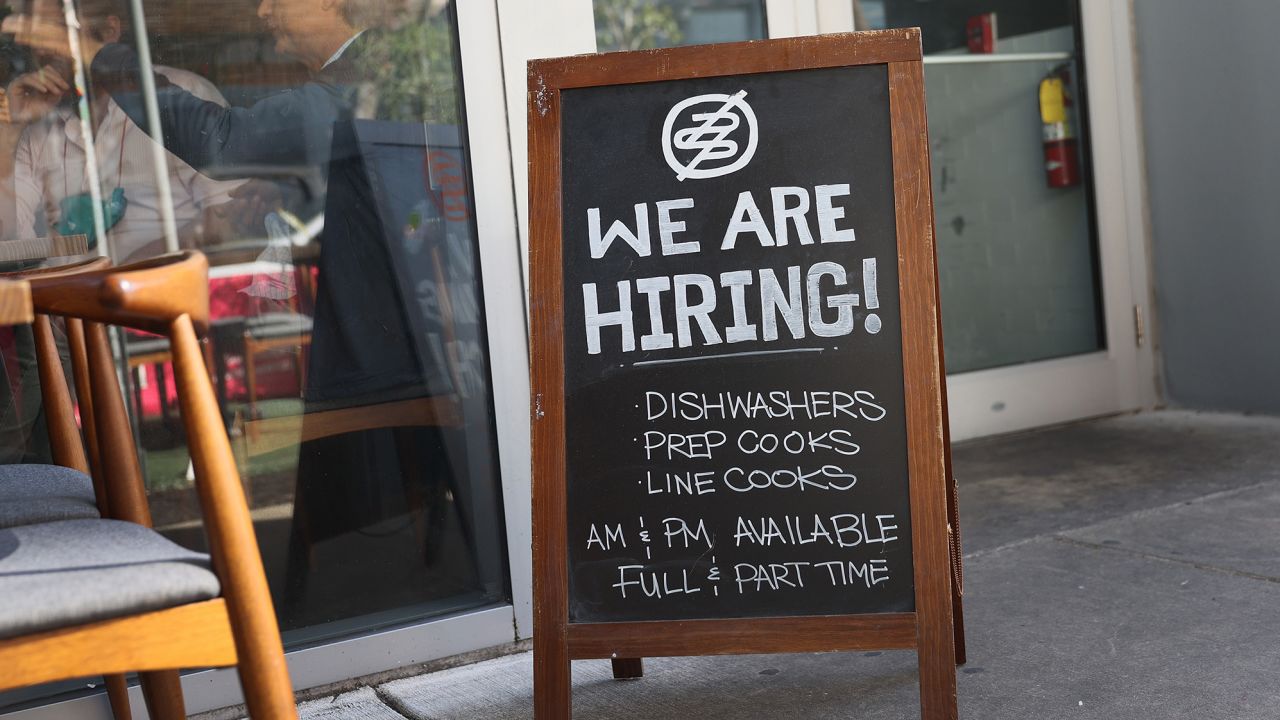 A 'we are hiring sign' in front of a restaurant in Miami.
