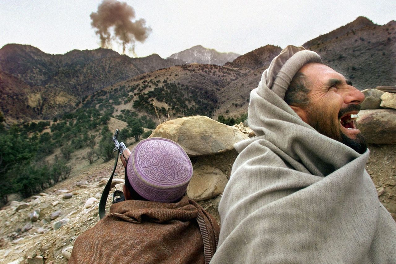 An Afghan Northern Alliance fighter bursts into laughter as US planes strike a Taliban position near Tora Bora, Afghanistan, in December 2001. Afghan militia leaders declared victory in the battle of Tora Bora and claimed to have captured al Qaeda's last base.