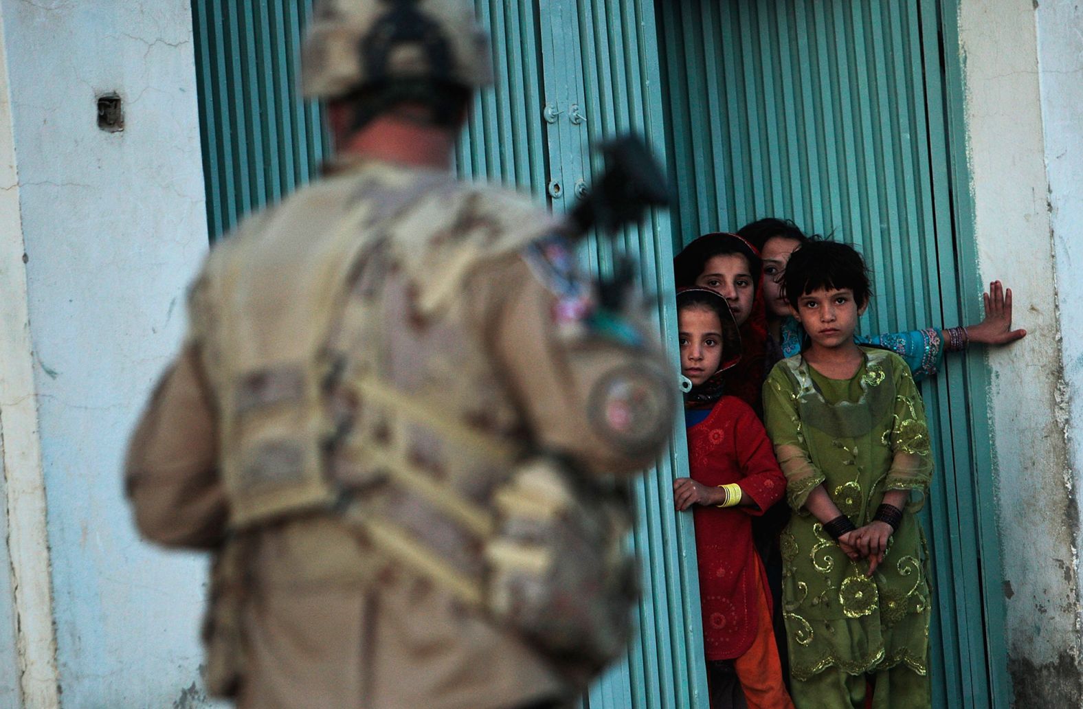 Children watch a Canadian soldier conducting a dusk patrol in Kandahar, Afghanistan, in October 2009.