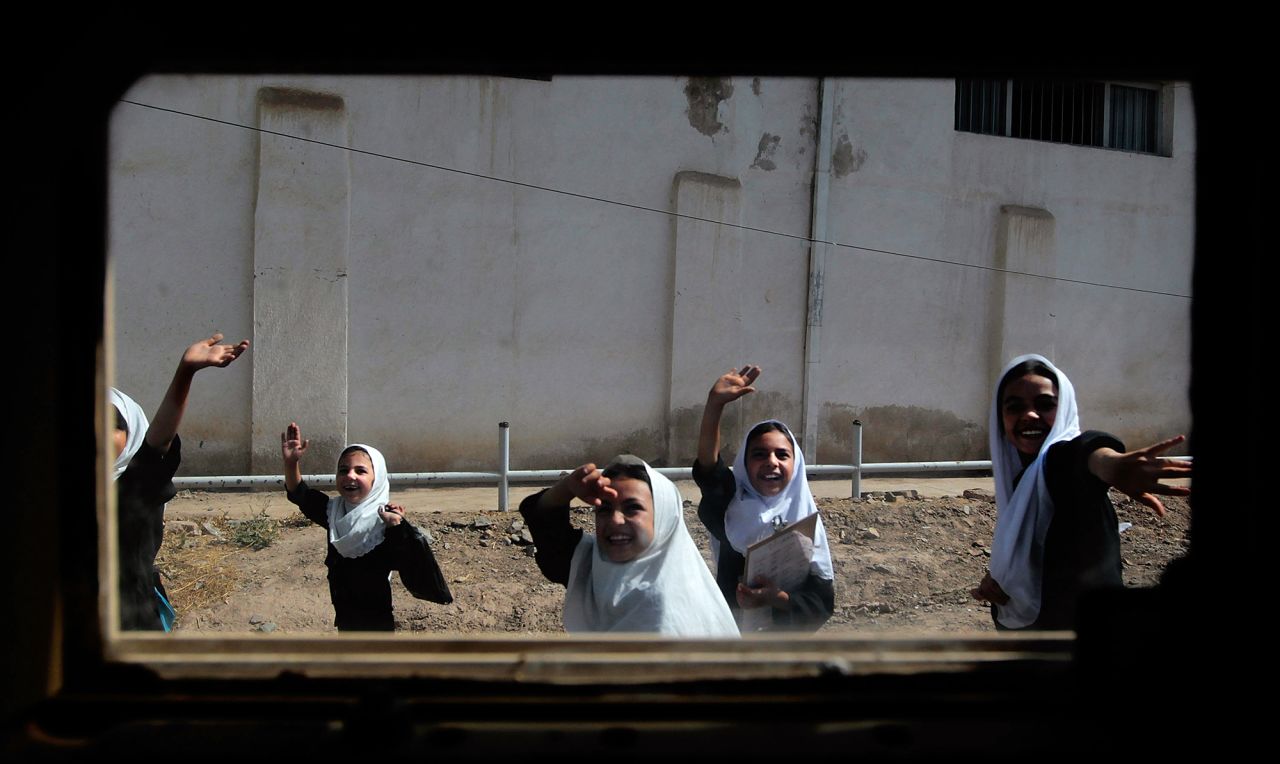 Schoolgirls are seen through the window of a Humvee as they wave to a passing American convoy in Herat, Afghanistan, in June 2010.