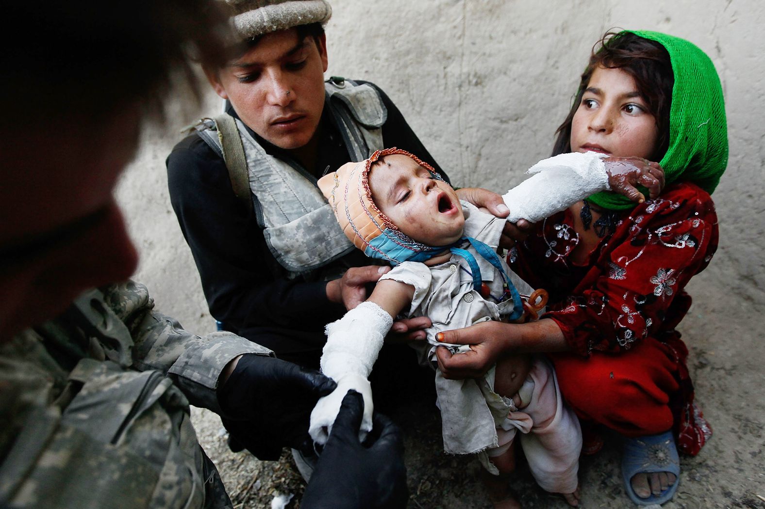 Halawasha, right, and an Afghan National Police member hold her young sister Shokria as a US Army medic wraps her serious burns in Now Ruzi, Afghanistan, in October 2010. US soldiers were on a routine patrol when they came across Shokria, whose forearms were burned with scalding milk during a household accident five days earlier. Medics dressed the burns and began working with local Afghan military to have the girl driven to a nearby hospital.