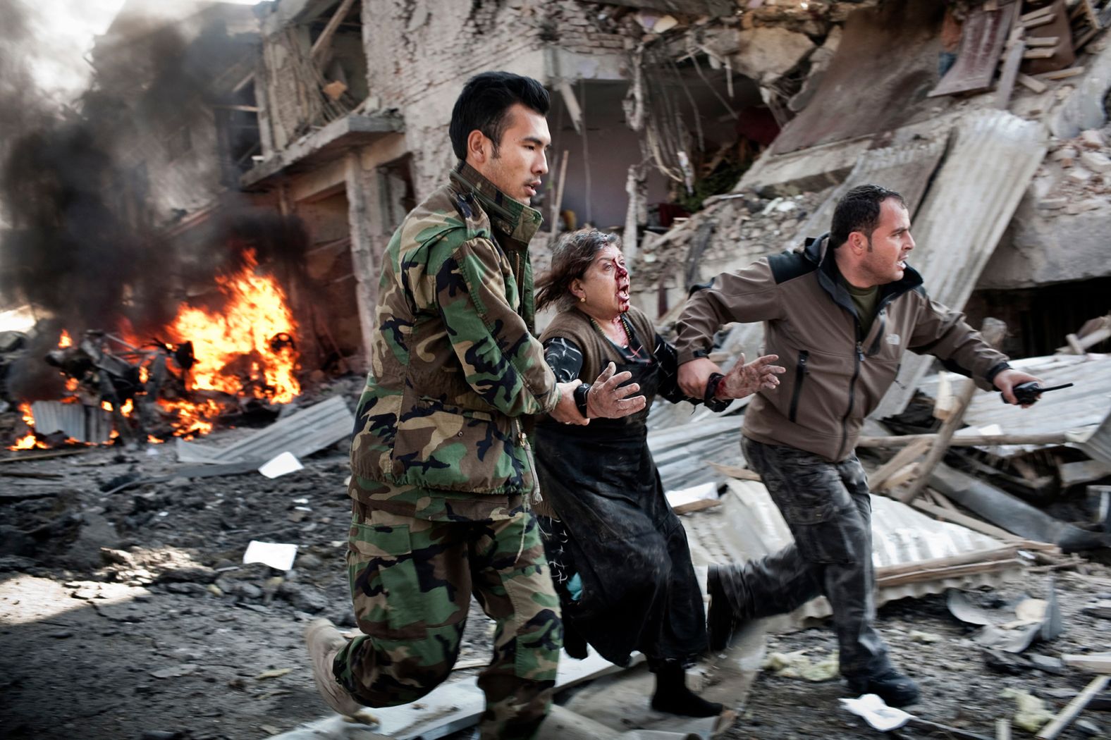 A woman is rushed from the scene of a suicide car bombing in Kabul in December 2013.