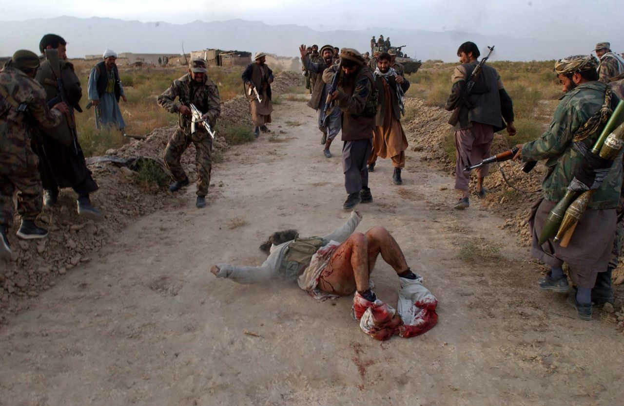 Members of the Afghan Northern Alliance, an anti-Taliban group, kill a wounded Taliban fighter they found while advancing toward Kabul, Afghanistan, in November 2001. US airstrikes and Northern Alliance ground attacks led to the fall of Kabul that month.
