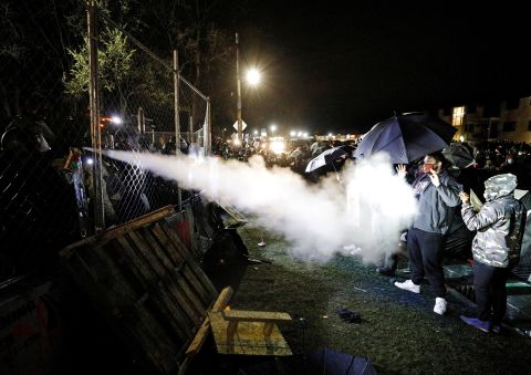 Pepper spray is used from behind the fenced perimeter of the Brooklyn Center Police Department on Wednesday.