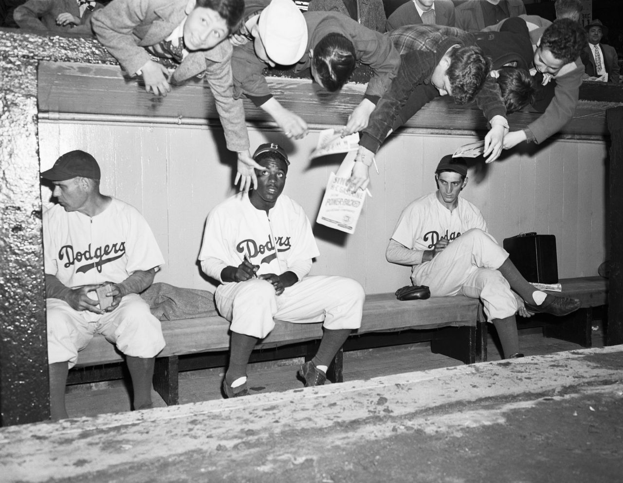 Young Dodger fans reach down to try to get Robinson's autograph during an exhibition game in New York on April 11, 1947.