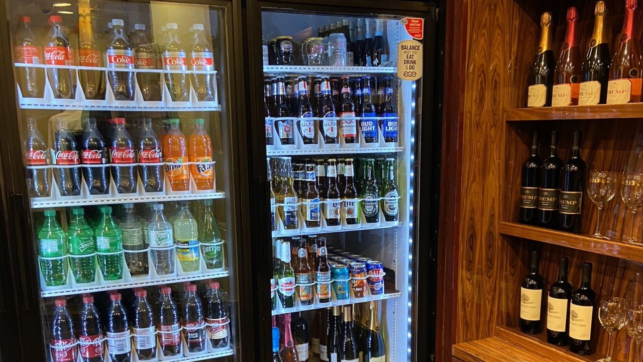 A fridge full of Coke beverages right near Trump wine bottles at Trump's Las Vegas hotel souvenir shop. 