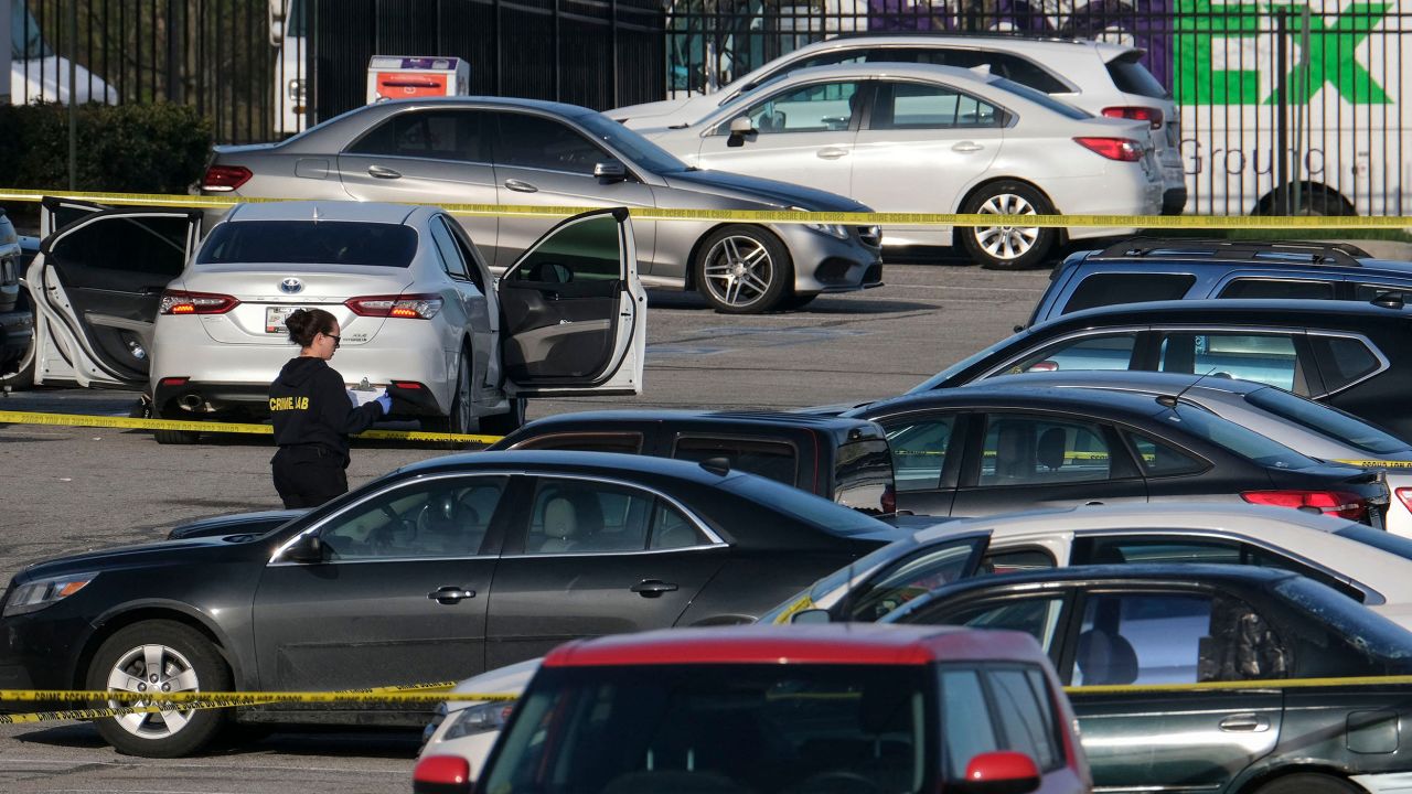 A crime lab technician works in the parking lot of the site of a mass shooting at a FedEx facility.