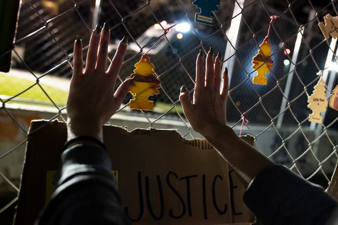 A demonstrator presses their hands against a perimeter security fence outside the Brooklyn Center Police Department. The fence is adorned with car air fresheners symbolic to the shooting death of Daunte Wright. Moments before police fatally shot Wright during a traffic stop Sunday, he called his mother and <a href="https://www.cnn.com/2021/04/12/us/police-shooting-air-freshener-trnd/index.html" target="_blank">told her he'd been pulled over for hanging air fresheners from his rearview mirror.</a> Minnesota is one of at least several states with laws that prohibit hanging items from a vehicle's rearview mirror or affixing them to the windshield on the grounds that they could obstruct the driver's vision. Brooklyn Center Police Chief Tim Gannon told reporters that Wright was originally pulled over for an expired tag and that when officers approached his car, they saw an item hanging from the rearview mirror. Officers ran Wright's name and found a gross misdemeanor warrant, Gannon said.