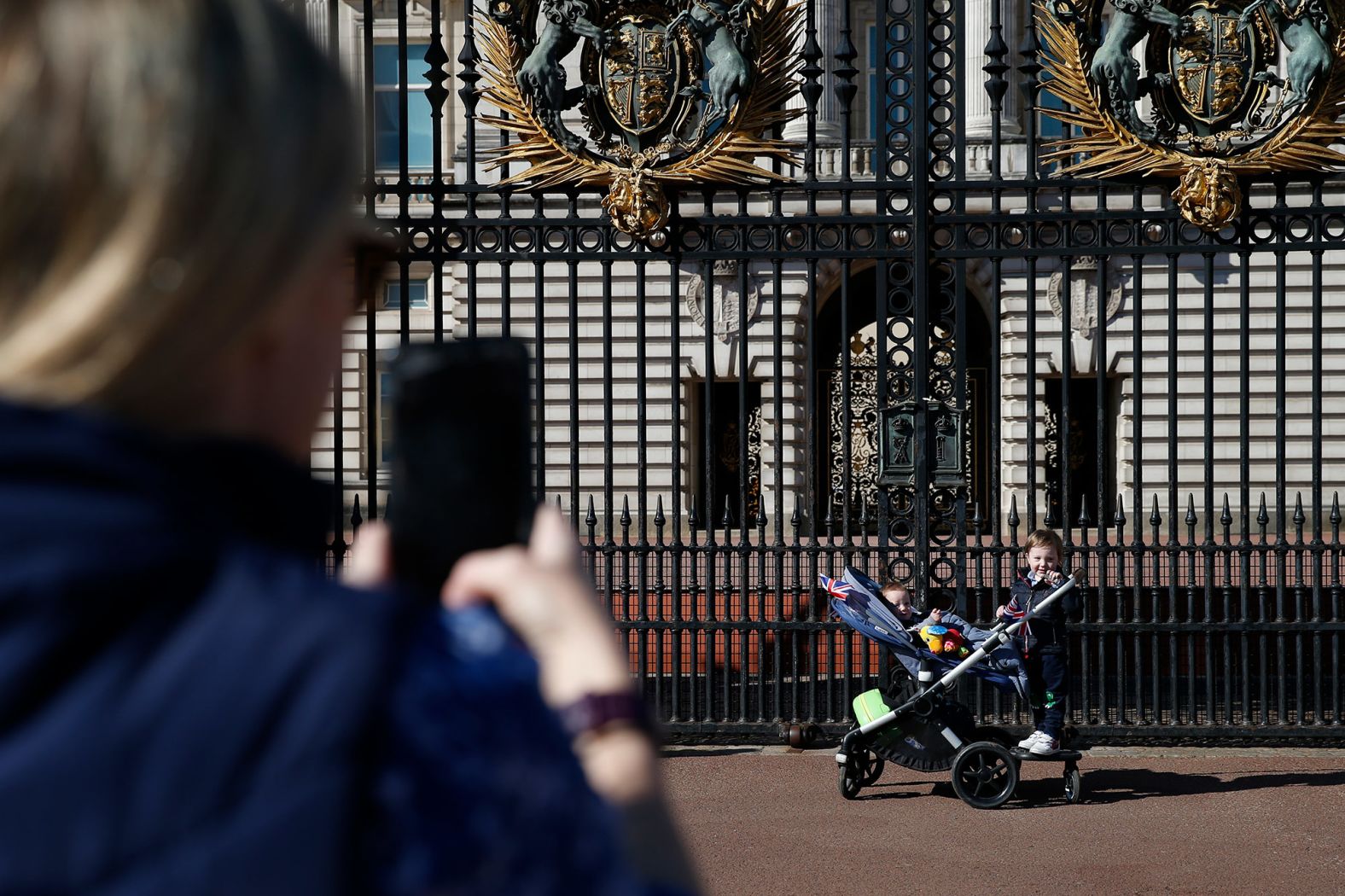 A woman takes a photo of her children outside Buckingham Palace on Saturday.