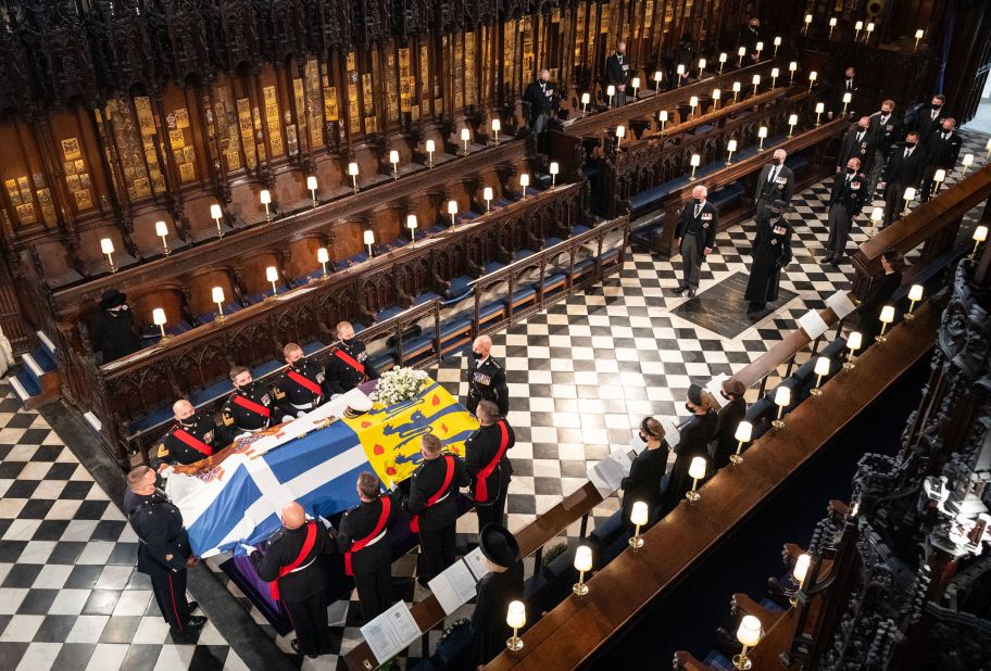 The Queen, left, watches as pallbearers carry Philip's coffin inside St. George's Chapel.