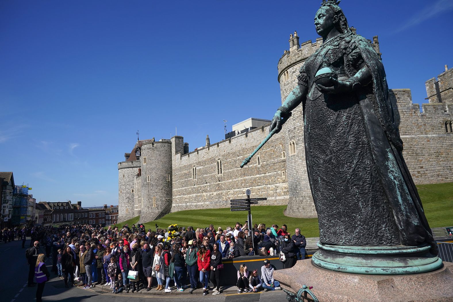 A crowd gathers near the Queen Victoria statue for a two-minute silence outside Windsor Castle during the funeral of Prince Philip.