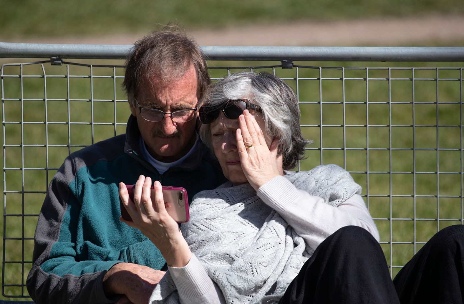 A couple watches the funeral of Prince Philip, Duke of Edinburgh, on their smartphone.