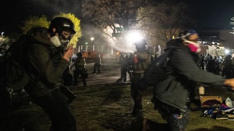 Law enforcement officers pepper spray freelance photographer Tim Evans (L) as he identifies himself a working journalist outside the Brooklyn Center police station on April 16.