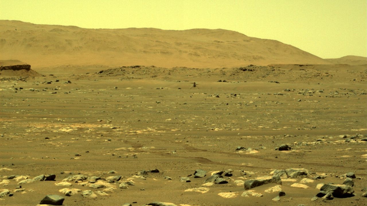 A view from the Perseverance rover shows Ingenuity with its blades in motion.