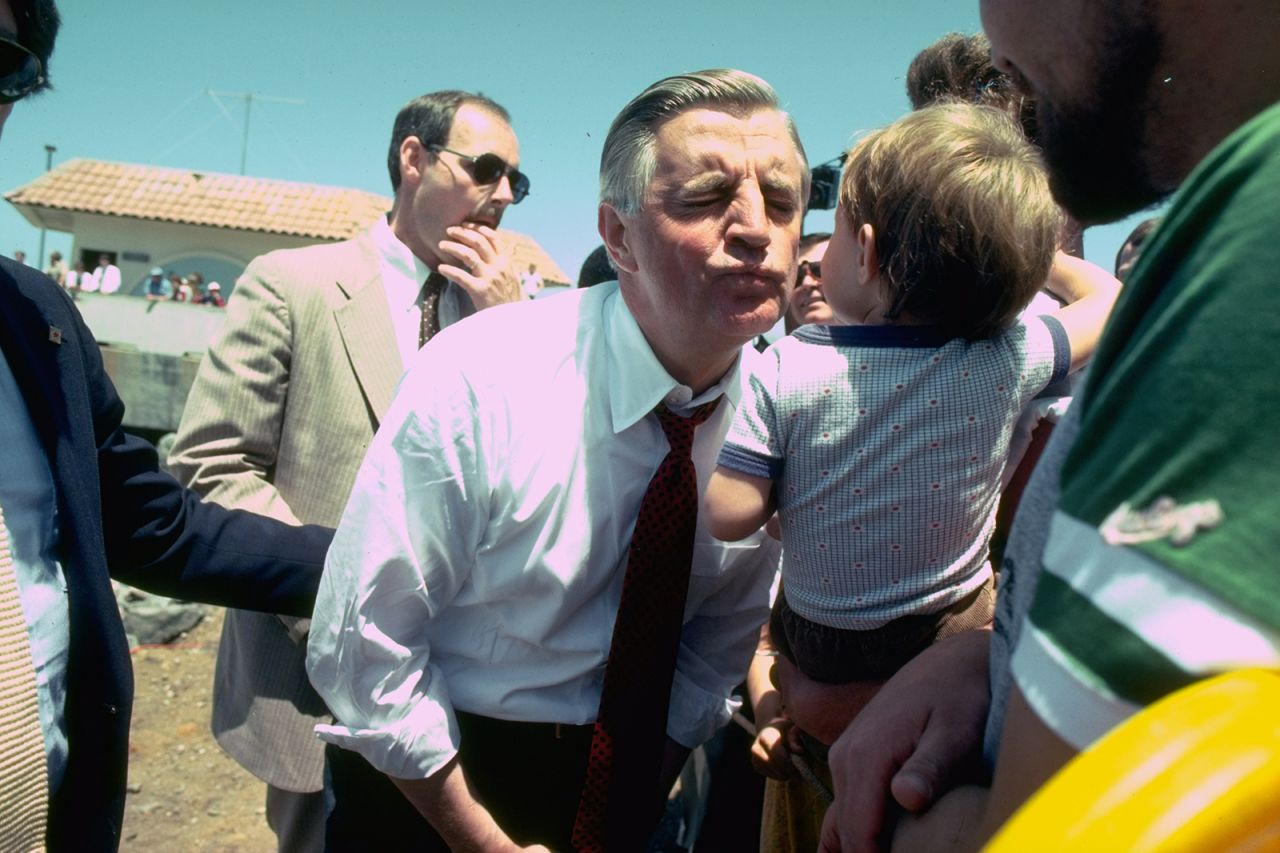 Mondale puckers up to kiss a child while campaigning in May 1984.
